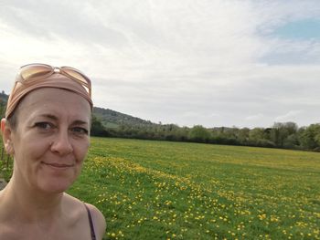 Portrait of smiling woman on field against sky