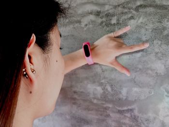 Close-up of woman wearing smart watch while gesturing against wall