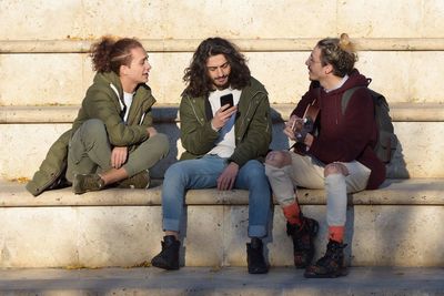 Cheerful friends sitting on staircase outdoors