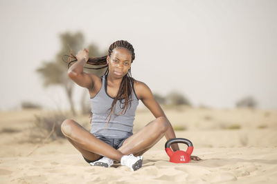 Full length of woman exercising in desert against sky