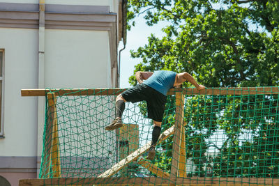 Low section of man by fence against trees