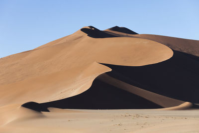 Sand dune in desert against clear sky