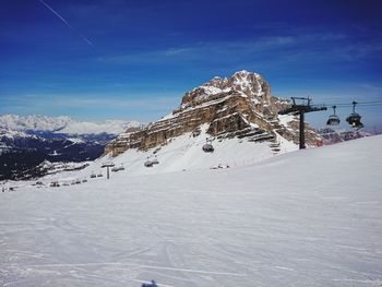 Snow covered land and mountains against blue sky