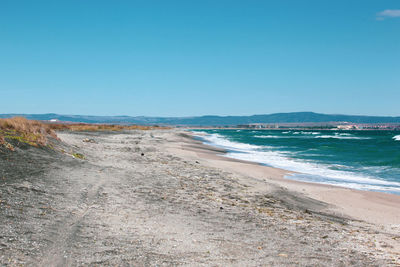 Scenic view of beach against clear blue sky