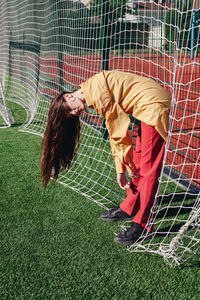 Full length of woman standing by soccer goal