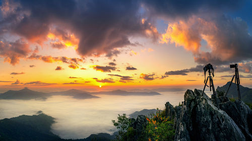 Silhouette of man standing on rock against sky during sunset