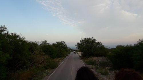 Road amidst trees against sky during sunset