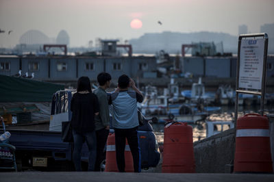 Friends standing at harbor during sunset