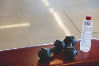 High angle view of bottle and dumbbell on table