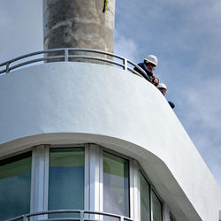 Low angle view of man standing by building against sky