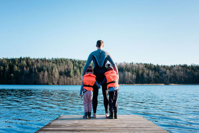 Father and his children standing on the end of a pier looking at sea