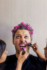 Cropped hands of children applying make-up on father face