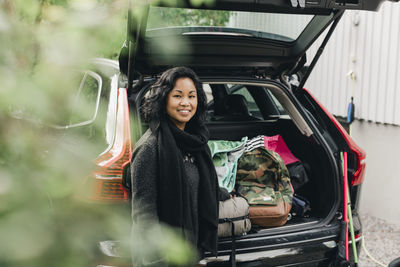 Portrait of smiling woman standing in car