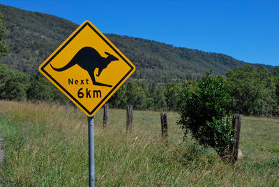 Road sign on field against clear sky