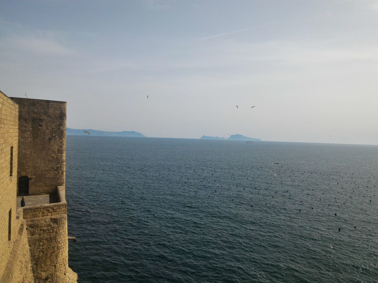 sea, water, sky, horizon over water, tranquility, tranquil scene, built structure, scenics, architecture, nature, building exterior, bird, beauty in nature, waterfront, day, idyllic, outdoors, cloud - sky, rippled, no people