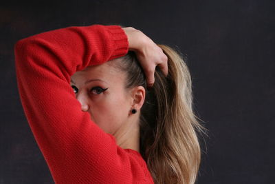 Portrait of young woman with hand in hair against gray background