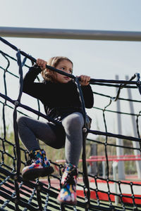 Four-year-old girl playing in the park, climbing in the daytime.