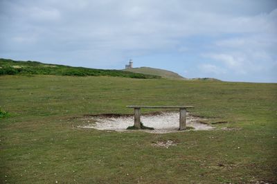 Seat on landscape against sky at birling gap