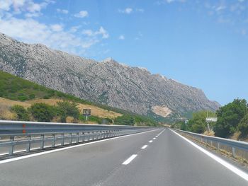 Empty road by mountain against sky