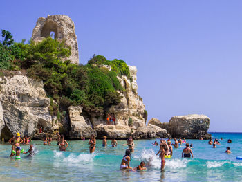 People at sea shore against clear sky