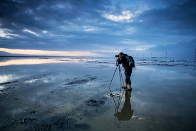 Man photographing at beach during sunset