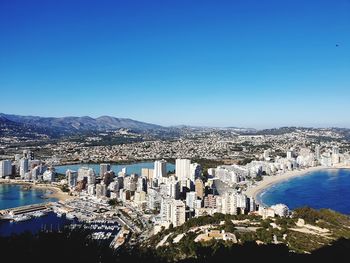 High angle view of city buildings against blue sky