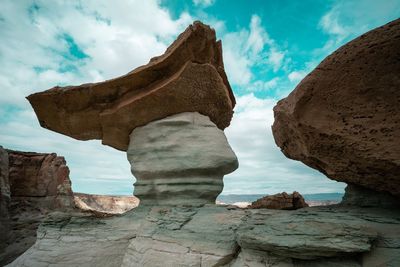 Low angle view of rock formations against cloudy sky