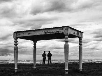 Men standing on beach against sky