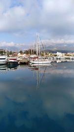 Sailboats moored at harbor against sky