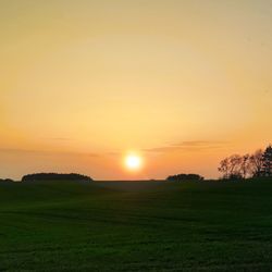 Scenic view of grassy field against sky during sunset