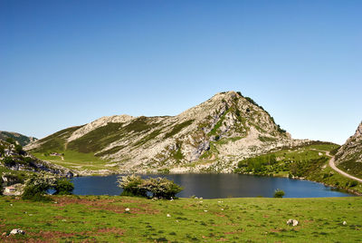 Scenic view of lake and mountains against clear blue sky