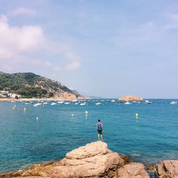 Man standing on rock by sea