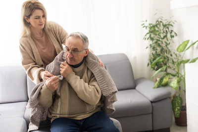 Side view of mother and daughter sitting on sofa at home