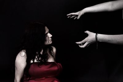 Woman looking at cropped hands gesturing against black background