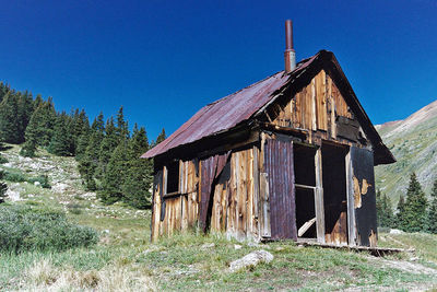 Abandoned house on field against clear blue sky