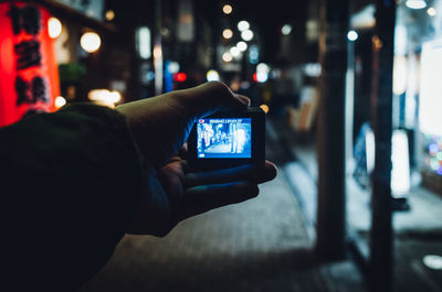 Close-up of hand using mobile phone at night