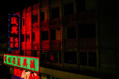 Illuminated text on building in city at night