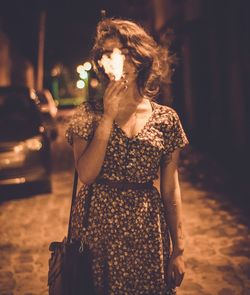 Young woman smoking on street at night