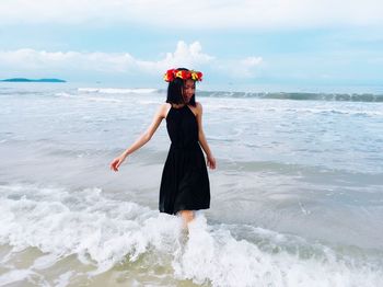 Young woman wearing flower tiara enjoying waves at beach