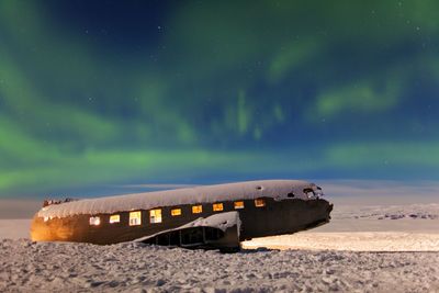 Abandoned bus on beach against sky at night