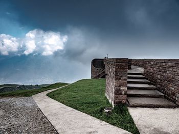 Stone wall with footpath against sky