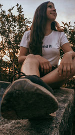 Young woman looking away while sitting on tree