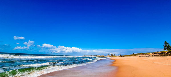 Scenic view of beach against blue sky