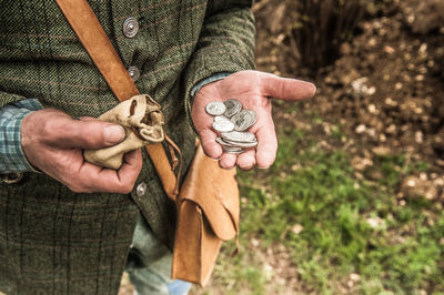 Midsection of man holding coins while standing outdoors