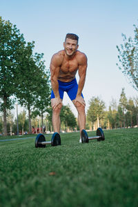 Portrait of shirtless man exercising on field