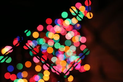 Illuminated colorful lights at night seen through silhouette fence