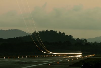 Light trails on bridge against sky at night