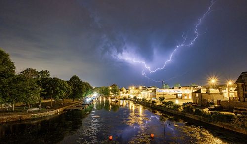 Lightning over a town reflected in water