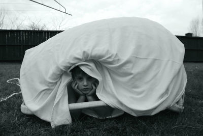 Portrait of boy under textile at backyard