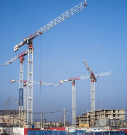 Cranes at construction site against sky